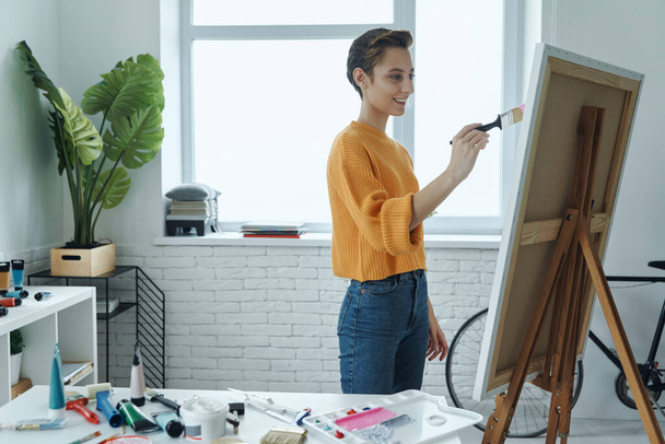 Beautiful young woman smiling while drawing in art studio - Фото, зображення