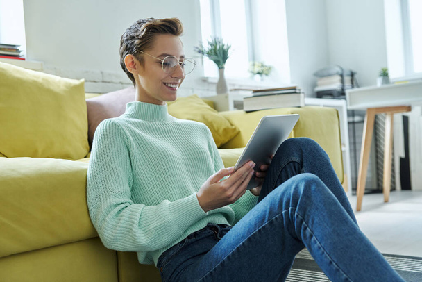 Confident young woman using laptop while sitting on the floor at home - Foto, Bild