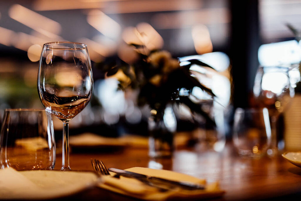 Luxury table settings for fine dining with and glassware, pouring wine to glass. Beautiful blurred background. Preparation for holiday wedding. Fancy luxury restaurant. - Φωτογραφία, εικόνα