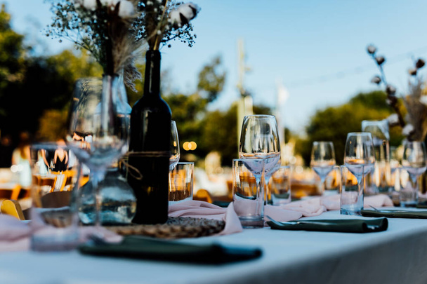 Luxury table settings for fine dining with and glassware, pouring wine to glass. Beautiful blurred background. Preparation for holiday wedding. Fancy luxury restaurant. - Foto, Imagen