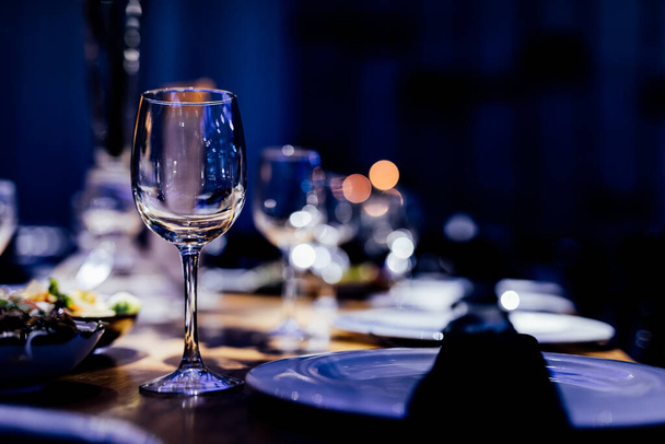 Luxury table settings for fine dining with and glassware, pouring wine to glass. Beautiful blurred background. Preparation for holiday wedding. Fancy luxury restaurant. - Photo, image