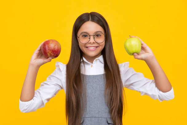 Vers fruit. Tiener meisje houdt appels op gele geïsoleerde studio achtergrond. Kindervoeding. Gelukkig meisje gezicht, positieve en lachende emoties - Foto, afbeelding