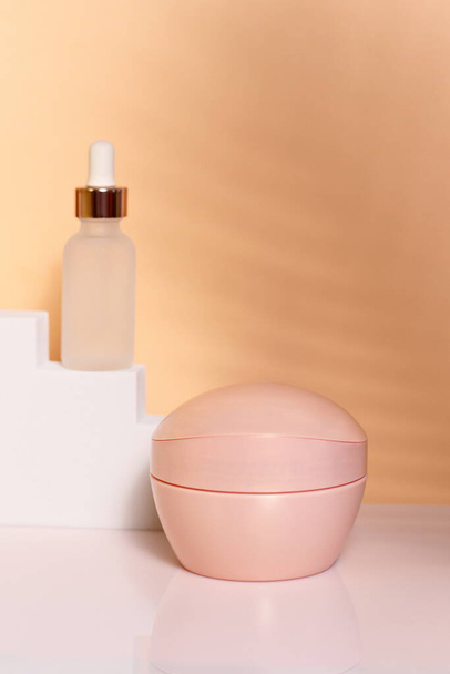 Roze cosmetische fles op witte trap, model omhoog, kopieerruimte - Foto, afbeelding