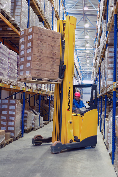 Yellow pedestrian stacker lifts pallet with boxes on the shelves - Foto, immagini