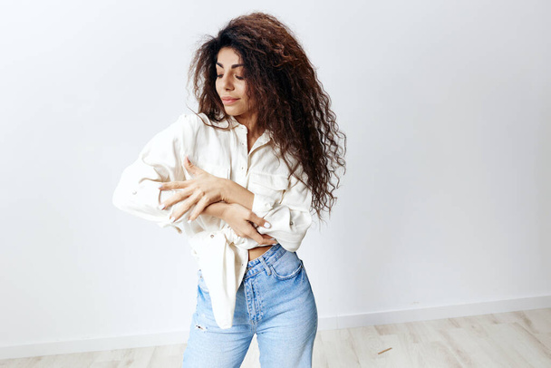 Eco Friendly Fashion Concept. Mujer latina con estilo feliz con pelo afro disfrutando de la camisa de lino blanco mirando a la mano aislada en el fondo del estudio blanco. Banner Mockup copia espacio libre lugar - Foto, Imagen