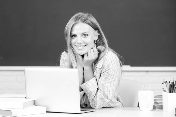 Portrait of smiling young college student studying in classroom. Creative young smiling female student using laptop - Foto, immagini