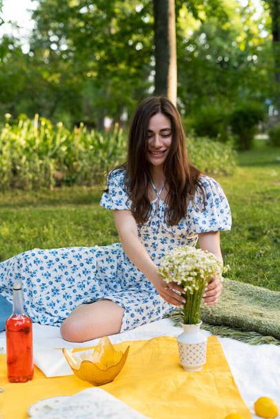 meisje in een blauwe jurk in het park bij een picknick op vakantie - Foto, afbeelding
