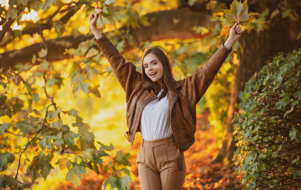 Beautiful girl enjoying autumn. Portrait of Young Woman Outdoor on Autumn Background - Foto, afbeelding