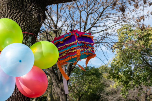 Luftballons und bunte Piata für eine Geburtstagsfeier im Park - Foto, Bild