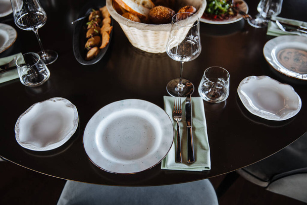 Bellamente organizado evento - mesa redonda servida banquete listo para los huéspedes, mesa redonda decorada con plato vacío, vasos, tenedores, servilleta. Elegante mesa de cena  - Foto, imagen