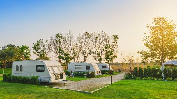 Cozy retro travel trailer Caravan on green grass before sunset near riverside in peaceful countryside. Family vacation travel RV, holiday trip in motorhome. Outdoor and Recreational Vehicles Theme. - Photo, Image