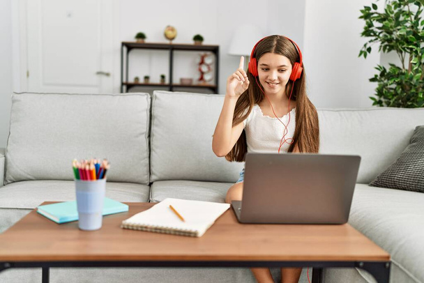 Adorable girl having online class sitting on sofa at home - Photo, Image