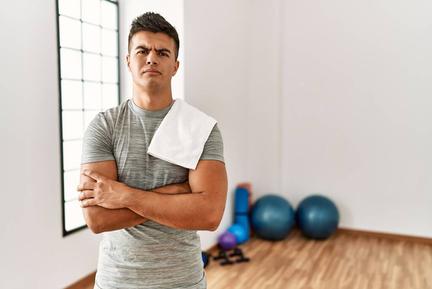 Young hispanic man wearing sportswear and towel at the gym skeptic and nervous, disapproving expression on face with crossed arms. negative person.  - Foto, imagen