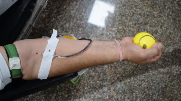 Донор крови в таборі для пожертвувань крові тримався з м'ячем, який тримається за руки в храмі Баладжі, Вівек Віхар, Делі, Індія. Крім того, щороку 14 червня в день донора світової крові постає концепція. - Кадри, відео