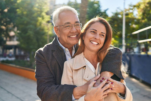 Чоловік і жінка середнього віку обіймають один одного стоячи в парку
 - Фото, зображення