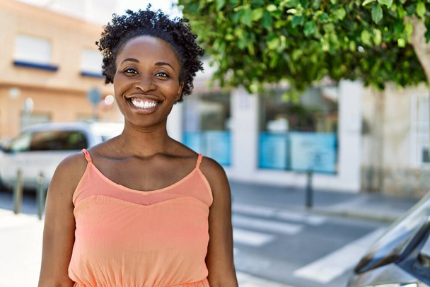Genç Afrikalı Amerikalı kadın bir yaz günü şehirde mutlu bir şekilde gülümsüyor. - Fotoğraf, Görsel