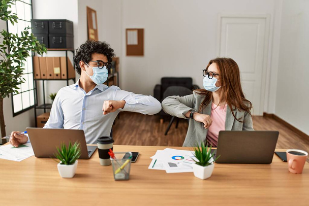 Dos trabajadores de negocios con máscara médica haciendo un apretón de manos en la oficina. - Foto, imagen