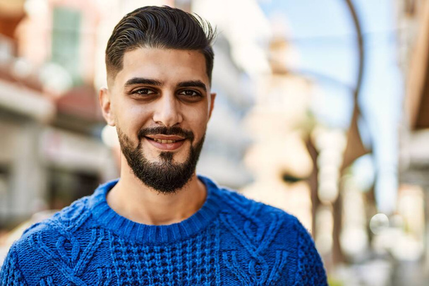 Young arab man smiling confident at street - 写真・画像