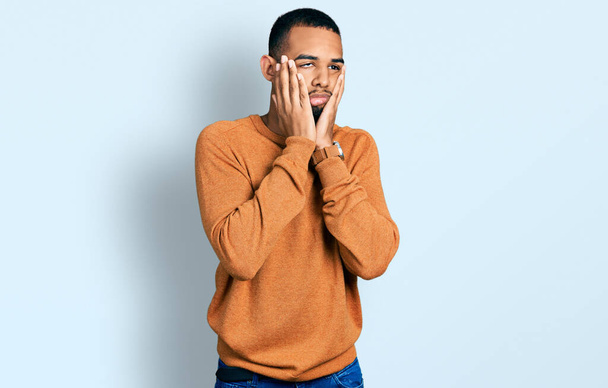 Junger afrikanisch-amerikanischer Mann in lässiger Kleidung, müde Hände, die Gesicht, Depression und Traurigkeit verdecken, verärgert und irritiert wegen Problemen  - Foto, Bild