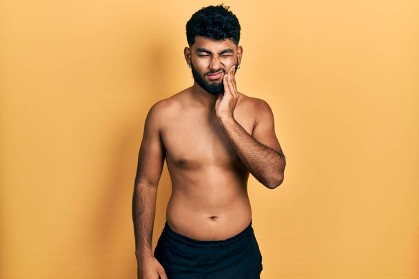 Arab man with beard wearing swimwear shirtless touching mouth with hand with painful expression because of toothache or dental illness on teeth. dentist  - Photo, Image