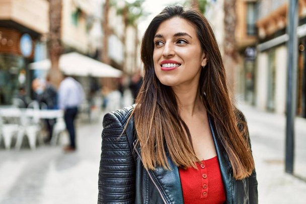 Молода іспаномовна дівчина посміхається щаслива стоячи в місті
. - Фото, зображення