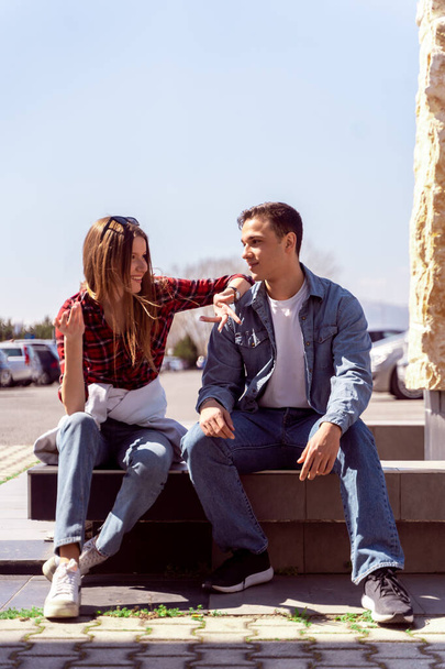 Χαριτωμένο ζευγάρι μιλάει ενώ κάθεται έξω - Φωτογραφία, εικόνα