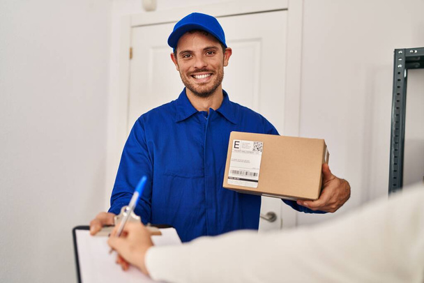 Young hispanic man courier holding package at home - Photo, Image