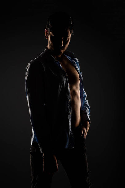 Bonito homem no estúdio fazendo poses em uma luz escurecido quarto na frente da câmera - Foto, Imagem