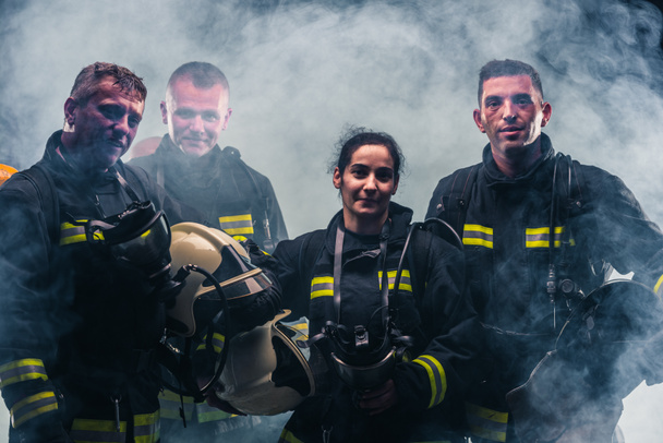 Equipo de bomberos de pie en medio del humo del extintor dentro del departamento de bomberos
 - Foto, imagen
