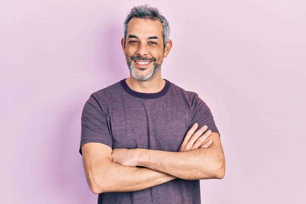 Handsome middle age man with grey hair wearing casual t shirt happy face smiling with crossed arms looking at the camera. positive person.  - Photo, Image