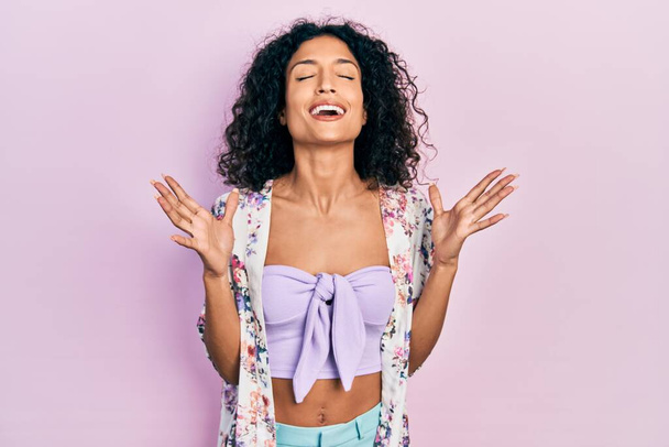 Nuori latino tyttö yllään rento vaatteita juhlii hullu ja hullu menestykseen kädet kohotetaan ja suljetut silmät huutaa innoissaan. voittajan käsite  - Valokuva, kuva