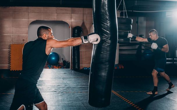 Mladí boxeři trénují boxerský pytel v tělocvičně. Kavkazský kick boxerky trénink s boxovací pytel v gym.Concept zdravého životního stylu - Fotografie, Obrázek