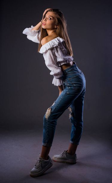 Кузовний знімок стильної жінки позує в модних рваних джинсах і білому бак-топ
 - Фото, зображення