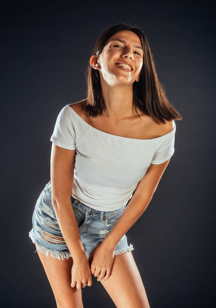 Крутая молодая девушка в современных джинсовых шортах и белом топе
 - Фото, изображение