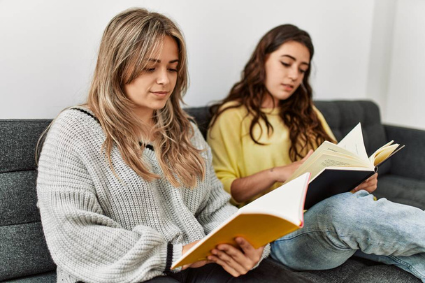 Mladý pár čtení kniha sedí na pohovce doma. - Fotografie, Obrázek