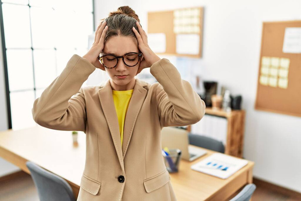 Mladá brunetka teenager nosit obchodní styl v kanceláři trpí bolestí hlavy zoufalý a ve stresu, protože bolest a migréna. Ruce za hlavu.  - Fotografie, Obrázek