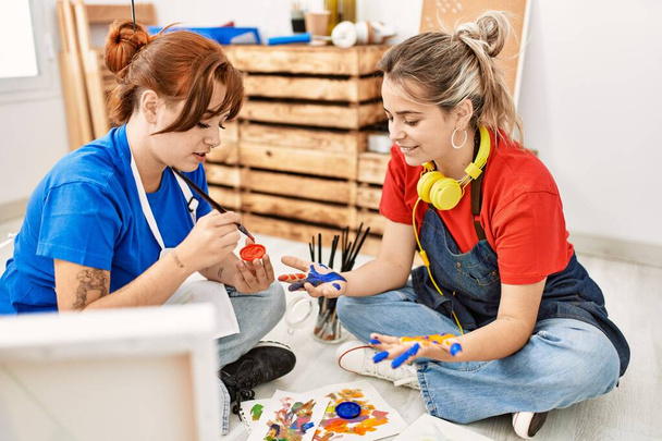 Két művész diák nő mosolyog boldog festmény kezét a művészeti iskolában. - Fotó, kép