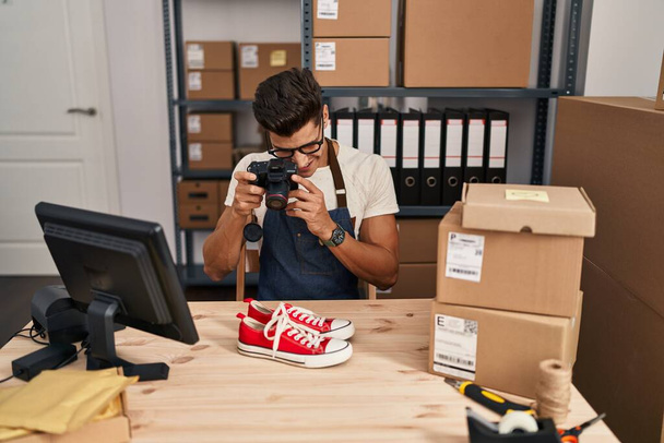 Молодой латиноамериканец из электронной коммерции делает фото для кроссовок в офисе - Фото, изображение