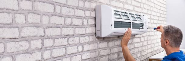 Mature Male Technician Fixing Air Conditioner With Screwdriver - Photo, Image