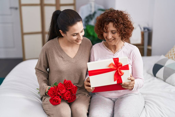 Dos mujeres madre e hija sorprenden con regalo y flores  - Foto, imagen