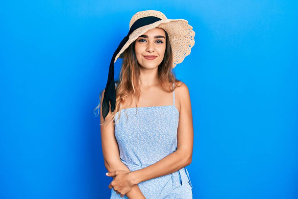 Νεαρή Ισπανίδα που φοράει καλοκαιρινό καπέλο με χαρούμενο και δροσερό χαμόγελο στο πρόσωπο. τυχερό άτομο.  - Φωτογραφία, εικόνα