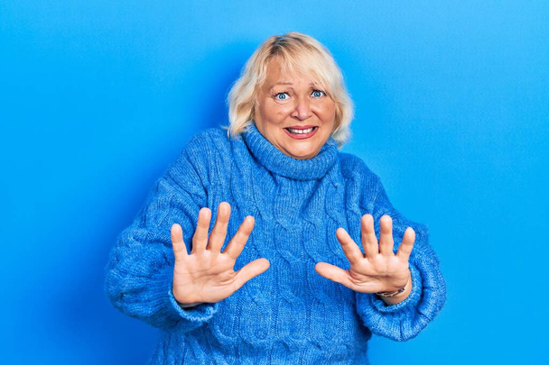 Middle age blonde woman wearing casual clothes afraid and terrified with fear expression stop gesture with hands, shouting in shock. panic concept.  - Foto, Bild