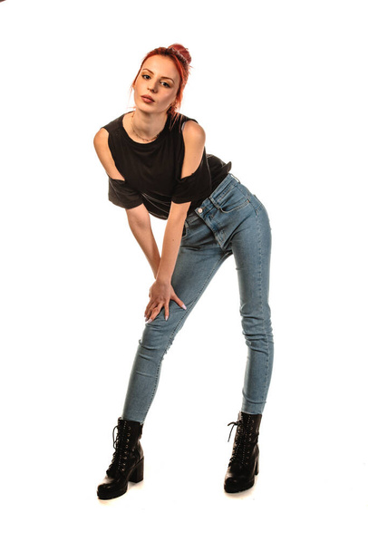 Body shot of a stylish woman posing in trendy jeans and black top against white background - Фото, изображение