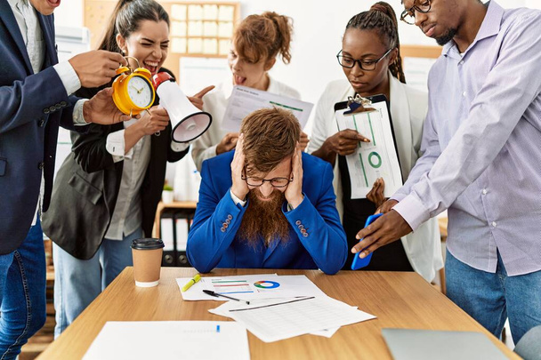 Groep van zakelijke werknemers schreeuwen naar gestresste partner op kantoor. - Foto, afbeelding