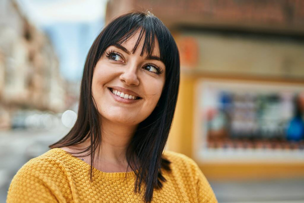 jong brunette vrouw glimlachen gelukkig naar de stad - Foto, afbeelding