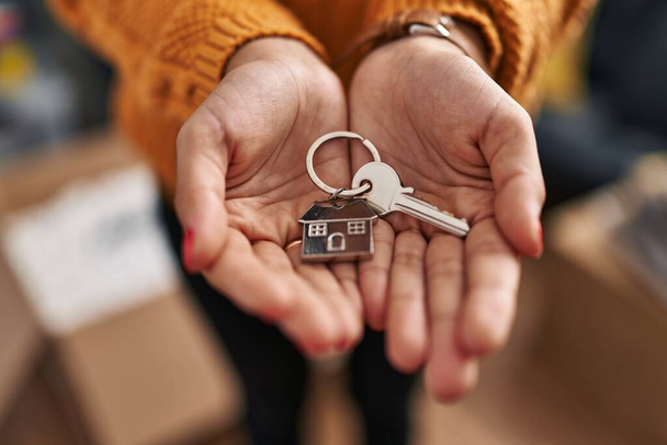 Jonge latijnse vrouw met sleutel van nieuw huis in nieuw huis - Foto, afbeelding
