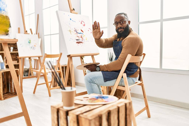 Afrykański amerykański artysta malarstwo człowiek na płótnie w studio sztuki z otwartą ręką robi znak stop z poważnym i pewnym siebie wyrazem, gest obrony  - Zdjęcie, obraz