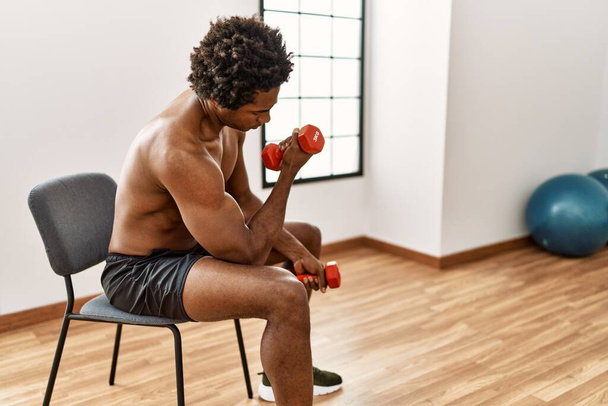 Joven afroamericano hombre entrenamiento usando mancuernas en el gimnasio - Foto, imagen