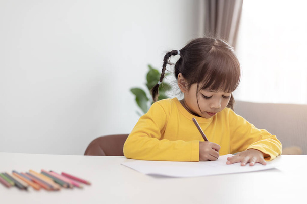 アジア系の小さな子供が家で宿題をする. - 写真・画像