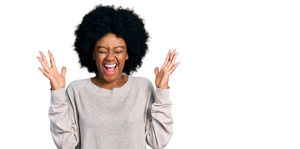 Joven mujer afroamericana vistiendo ropa casual celebrando loco y loco por el éxito con los brazos levantados y los ojos cerrados gritando emocionado. concepto ganador  - Foto, Imagen